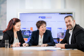 PIA Berater und Beraterinnen der Firma ImmoKonzepte GmbH sitzen an einem Tisch im Besprechungsraum und lächeln freundlich